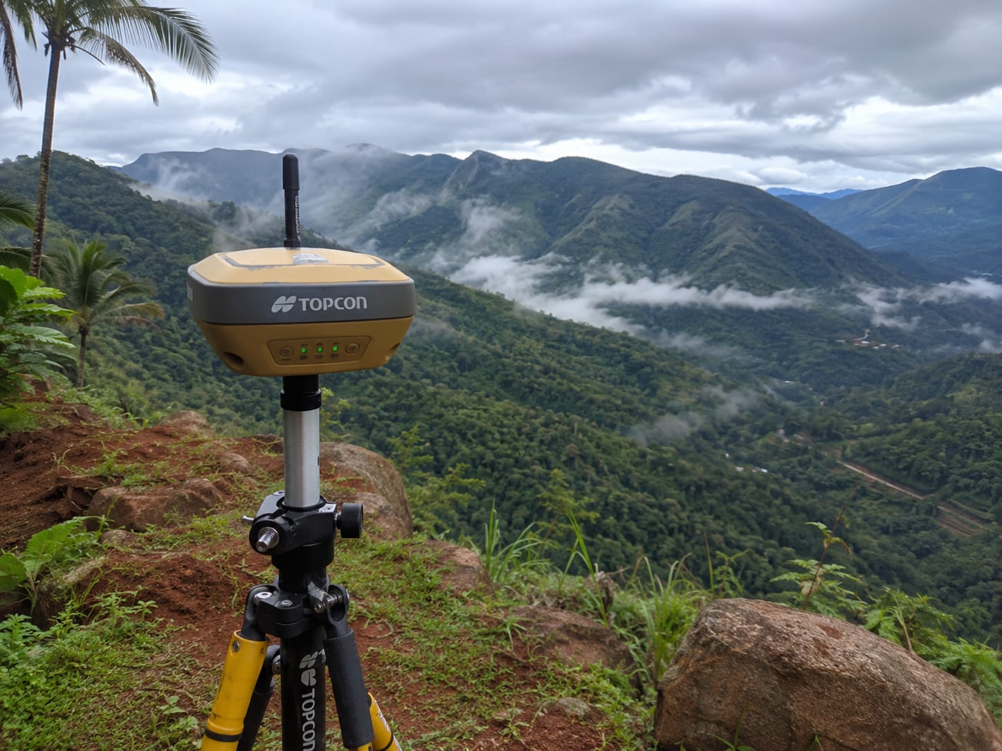 Topcon GNSS/GPS rover on a tripod against Kerala's lush hillside — satellite-based RTK survey by Static Survey Solutions